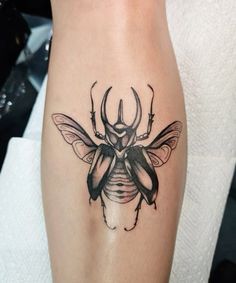 a tattoo on the leg of a woman with a bug in it's center