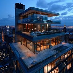 an aerial view of a modern building in the city at night, with lights on