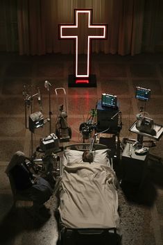 a hospital room filled with medical equipment and a cross on the wall above it's bed