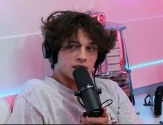 a young man with headphones on sitting in front of a microphone