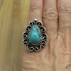 This is a very beautiful vintage sterling silver teardrop turquoise ring. There is a lovely lacey silver design around the stone. The whole face of the ring is 32 mm X 24 mm, and is 8 mm thick. The turquoise stone is 20 mm X 13 mm. The band is 3 mm wide. There are no visible hallmarks on this piece but it is guaranteed sterling silver. The ring weighs 10.8 grams and is a size 5.25. We can size most rings for an additional fee, please message me what size you need and I will get back to you with Bohemian Adjustable Teardrop Turquoise Ring, Unique Handmade Teardrop Turquoise Ring, Bohemian Teardrop Turquoise Ring In Silver, Handmade Blue Turquoise Teardrop Ring, Bohemian Sterling Silver Turquoise Teardrop Ring, Turquoise Stone, Vintage Sterling Silver, Turquoise Ring, Statement Rings