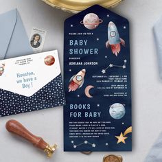 a baby shower bookmark next to an envelope and some other items on a table