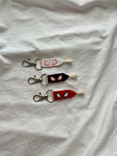 three red, white and black keychains with the word love on them are laying on a white sheet