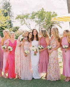 a group of women standing next to each other wearing dresses and holding bouquets in their hands