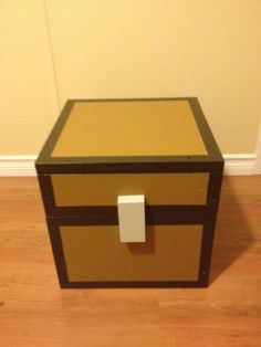 a brown and tan box sitting on top of a hard wood floor next to a wall