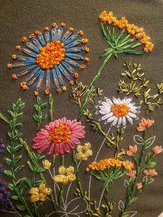 a close up of some flowers on a piece of cloth with stitching in the middle