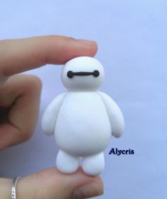 a hand holding a small white toy in it's palm