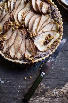 an apple pie with walnuts and pecans in it on a table next to a knife