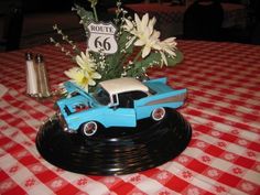 a table with a red and white checkered tablecloth has a blue toy car on it