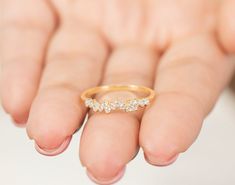 a woman's hand holding a gold ring with three small white diamonds on it