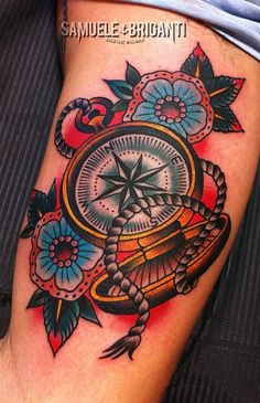 a close up of a person's leg with a compass and flowers on it