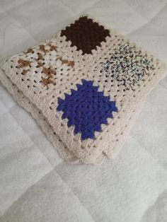 a crocheted blanket on top of a bed covered in white and blue blankets