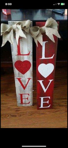 two vases decorated with red and white painted wood are sitting on a wooden floor