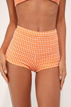 Beach days aren't complete without the Dippin' Daisy's Farrah Orange Gingham Swim Shorts! Crinkly stretch-knit, with a white gingham pattern, creates an elasticized high-waist and skimpy bottom coverage, perfect for pairing with your bikini top. PLEASE NOTE: Swimwear returned without the hygienic liner is non-refundable. Fit: This garment fits true to size. Length: Above mid-thigh. Size medium Inseam: 1.25 Front Rise: 10.00 Waist: Fitted - stretchy fabric allows custom fit. Hip: Fitted - stretch Gingham Bottoms With Elastic Waistband And Short Length, Trendy Gingham Bottoms In Short Length, Trendy Gingham Bottoms Short Length, Trendy Gingham Short Bottoms, Trendy Gingham Short Length Bottoms, Plaid Bottoms With Elastic Waistband And Short Length, Plaid Bottoms With Elastic Waistband, Gingham Bottoms For Beach And Summer, Gingham Summer Beach Shorts