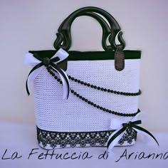 a white and black handbag with a bow on it