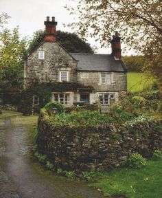 an old stone house surrounded by greenery and trees