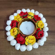 a candle holder made out of flowers on top of a wooden table next to a mirror