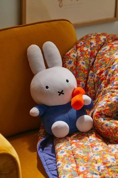 a stuffed rabbit sitting on top of a couch next to a pillow and chair cover