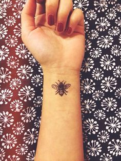 a woman's arm with a small bee tattoo on the left side of her wrist