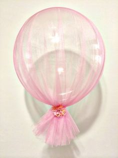 a large pink balloon sitting on top of a white wall