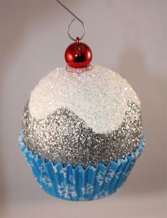 a cupcake ornament hanging from a string on a white background with snowflakes