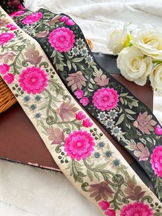 a close up of a flowered ribbon on a table with flowers in the background