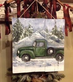 an old green truck painted on wood hanging from a mantel above a christmas tree