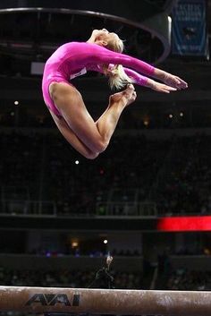 a woman is doing a handstand on the balance beam