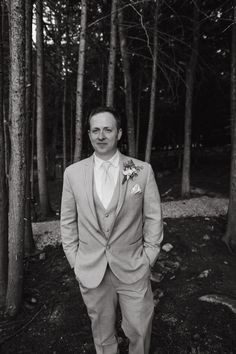 a man in a suit standing next to some trees