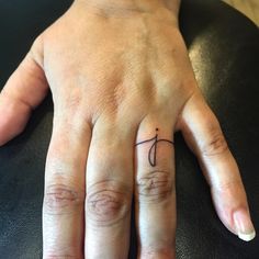 a person's left hand with a small tattoo on the middle finger and an initial