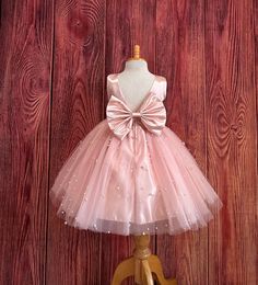 Little Darln Boutique  Our enchanting Knee Length flower girl dresses are sure to turn heads! This beautiful elegant sophisticated dress is handmade, the bodice consists of Blush Bridal Satin with a sowed in sash at the waist, the back of the dress consists of an open V-back with a hidden zipper. The big bow is detachable. The skirt consists of 4 Blush layers of tulle with the top layer consisting with sowed in pearl beads. The fifth layer is made of lining with crinoline for fullness.  This dress is perfect for any occasion!  Dress Is Pictured with a petticoat NOT INCLUDED https://www.etsy.com/listing/1316417982/white-knee-length-petticoat-wedding?click_key=41cb8b0ae4587efa582b0a433f3f5e0cde12aec0%3A1316417982&click_sum=af1df37b&ref=shop_home_active_1 Visit our store, more items to come! Flower Girl Dresses Peach, Pink Bridesmaid Dress For Pageant, Princess Style Pink Bridesmaid Dress For Pageant, Pink Princess Bridesmaid Dress, Pageant Tulle Dress With Satin Bow, Tulle Dresses With Satin Bow For Pageants, Tulle Dress With Satin Bow For Pageant, Elegant Pink Bridesmaid Dress For Pageants, Elegant Pink Bridesmaid Dress For Pageant