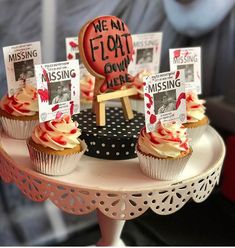 some cupcakes are sitting on a cake stand with signs and magnets attached to them