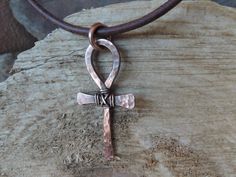 "This hammered and textured solid copper metalwork Ankh cross is a totally handmade piece of jewelry that can be for him or her! The cross has wire wrap around the center to add to its rustic look. A patina is added to the cross for a vintage weathered look. As a final touch, the cross is polished and sealed to avoid natural oxidation process. It measures about 1.7 inches x 0.8 inches / 4.3 cm x 2.1 cm. The pendant is hung on a 1/8\" / 2.5 mm genuine leather cord featuring a secure handmade hook Handmade Bronze Crucifix Jewelry, Copper Cross Jewelry For Gifts, Artisan Adjustable Cross Jewelry, Unique Adjustable Cross Jewelry, Adjustable Unique Cross Jewelry, Artisan Hand Forged Cross Jewelry, Artisan Brown Cross Jewelry, Handmade Adjustable Cross Pendant Necklace, Handmade Brown Crucifix Jewelry