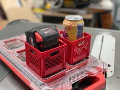 two red baskets with drinks in them sitting on top of a plastic tray next to a laptop