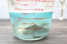 a measuring cup filled with blue liquid on top of a wooden table