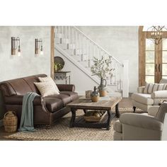 a living room with two couches and a coffee table in front of the stairs