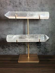 the three tiered glass display stands are on a wooden table next to a gray wall