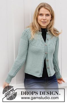 a woman leaning against a white wall wearing a green cardigan