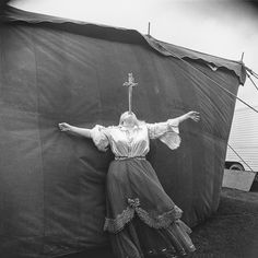 an old photo of a woman standing in front of a tent with her arms outstretched