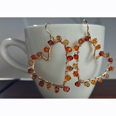 a pair of earrings sitting on top of a white cup in front of a mug