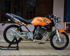 an orange and black motorcycle parked on top of a tiled floor next to a building