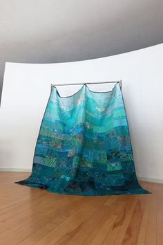 a blue and green blanket sitting on top of a wooden floor next to a white wall