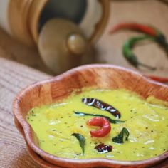 a wooden bowl filled with yellow food on top of a table