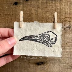 a hand holding a small piece of paper with a drawing of a bird on it