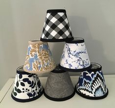 four different shades of lampshades on a white counter top, one is blue and the other is black