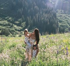 a woman and two children walking through a field