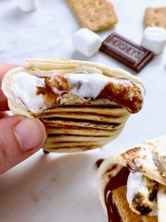 a person is holding up some food with marshmallows and chocolate on it