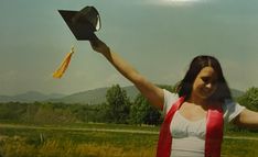 a woman holding up a black hat in the air