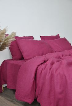 a bed with pink sheets and pillows on top of it next to a white wall