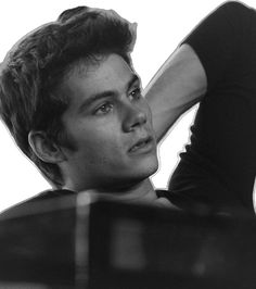 black and white photograph of a young man leaning on a piano